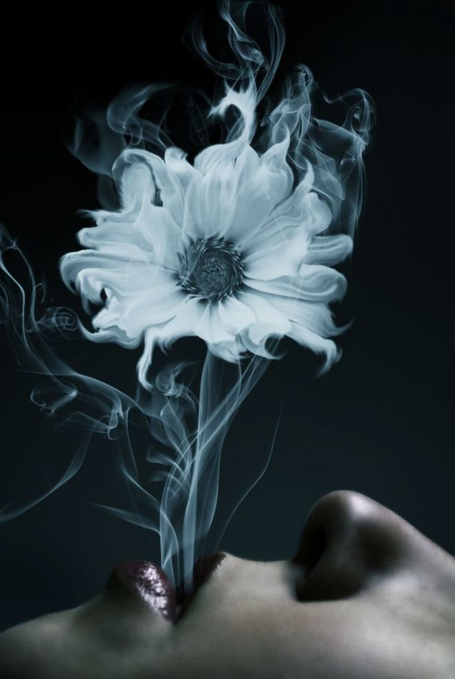 woman blowing vapor with flower